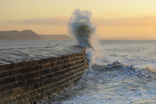 Big Waves Splashing On The Cobb In Lyme Regis, Dorset Caused By Gusty Winds During High Tide