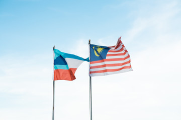 Malaysia and Sabah flags waving with blue sky in the background.