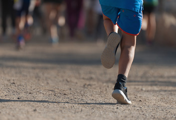 Fototapeta na wymiar Running children, young athletes run in a kids run race,running on city road detail on legs