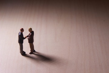 Obraz premium Dramatic Lighting, Simple Illustration Photo for Two Mini Figure Businesman Toy Handshaking for Business Agreement 