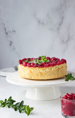 Classical New York cheesecake with cranberry sauce, mint and rosemary, light grey stone background. 