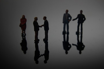 Dramatic Lighting, Simple Illustration Photo for Silhouette Two Miniature Figure Man Toy Handshaking for Business Agreement between they team 