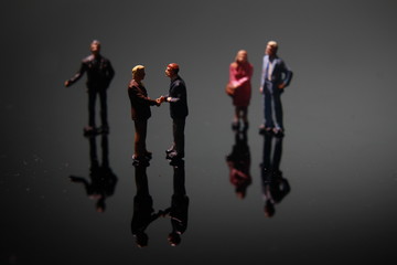 Dramatic Lighting, Simple Illustration Photo for Two Miniature Figure Man Toy Handshaking for Business Agreement between they team 