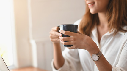 Fototapeta premium Closeup female holding her coffee cup in home office.