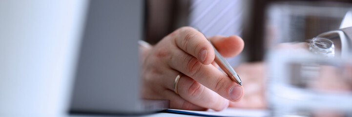 Male arm in suit and tie hold silver pen filling schedule