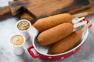 Corn dogs with mustard over beige stone background, studio shot, selective focus