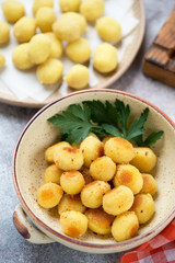 Naklejka na ściany i meble Bowl of pan fried potato gnocchi with uncooked gnocchi in the background, vertical shot, closeup