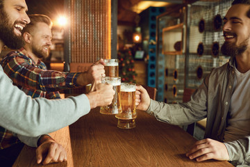 Group friends clinking glasses of beer in a bar.