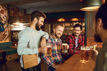 Group of male friends drink beer at a party in a bar.