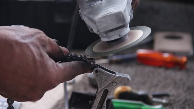 Many sharp sparks from motorcycle mechanic using old electric grinder with  motorcycle roller chain closeup background