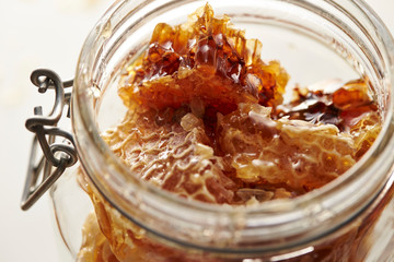 Honeycomb in glass jar on white background 