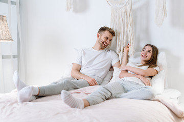 Young adult boyfriend and girlfriend spending morning in bedroom