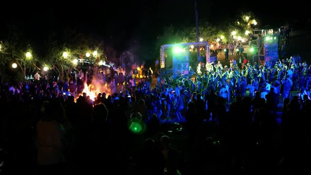 Celebration holiday feast. Night Beach Disco concert with colorful illumination and bonfire. Dancing people with fun gladness on the discotheque entertainment. Gaiety merriment of youth 