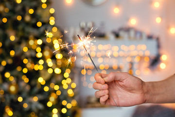 burning Sparkler on background of Christmas tree and bokeh garland