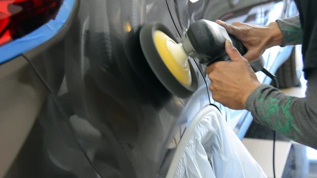 A man works at polishing the car after washing the car. Car polishing removes the scratches before waxing.