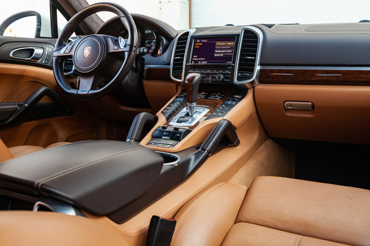 The interior of the car Porsche Cayenne 958 2011 year with a view of the steering wheel, dashboard, seats and multimedia system with light brown leather trim