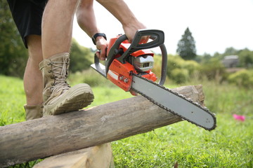 a man saws off a log with a chainsaw close up