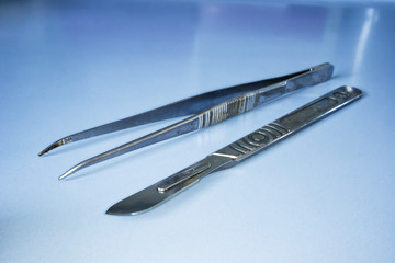 Scalpel and laboratory tweezers on a laboratory table. Labware