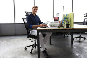 Young modern business man working using digital tablet while sitting in the office.