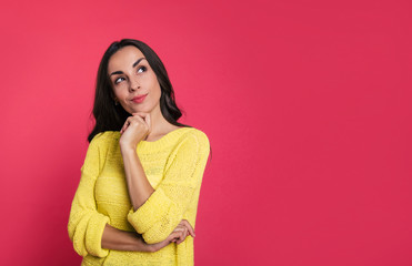 What else to do?  Close-up photo of a happy young woman in a yellow sweater, who is daydreaming with her left hand near her chin and her right arm folded.