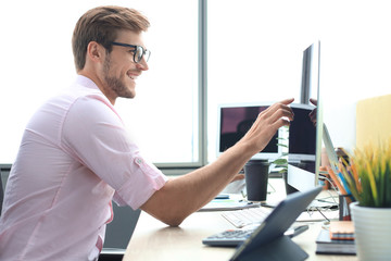 Thoughtful young business man in shirt working using computer while standing in the office.