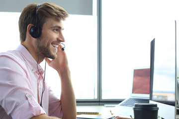 Happy young male customer support executive working in office.
