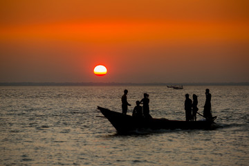 Fototapeta premium Colorful golden Sunset on Sea. Fishermans are returning home with fish, manually at sunset on Char Samarj beach at Chandpur, Bangladesh.