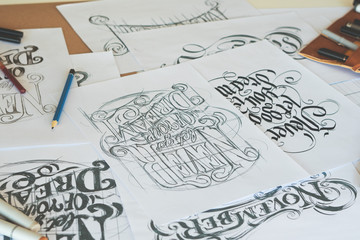 Typography Calligraphy artist designer drawing sketch writes letting spelled pen brush ink paper table artwork.Workplace design studio.