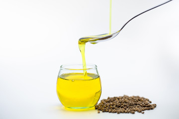 Hemp seeds, Pouring hemp oil into a glass jar on white background, CBD Cannabis  oil Extract.
