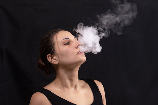 Portrait of girl blowing smoke water vapor from vape