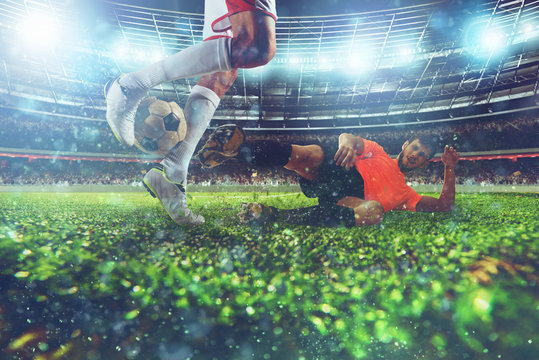 Close up of a football action scene with competing soccer players at the stadium during a night match