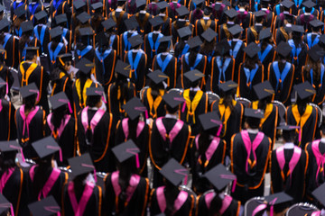 Fototapeta premium Rear view and soft selective focus of the graduates in the graduation commencement ceremony recieving diploma degree certificate.