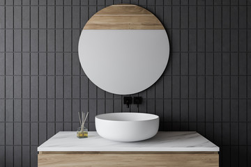 Gray tile bathroom with sink and round mirror