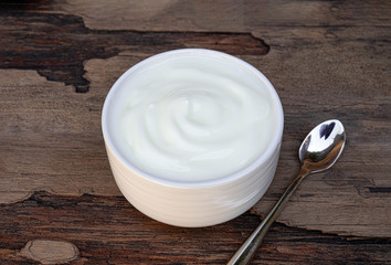 Yogurt greek white clean In bowl with spoon on a wooden background.