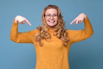 Sincere and attractive friendly looking pleasant woman with blond hair smiling broadly and pointing...