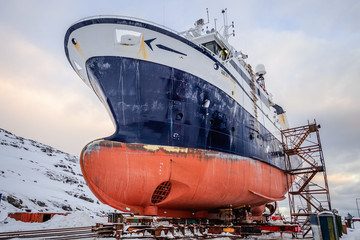 Fishing ships hulls in a dockyard on maintenance during the winter time, port of Nuuk, Greenland