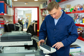 Portrait of confident service engineer standing by photocopy machine in office