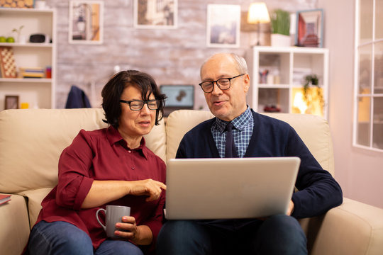 Elderly old couple using modern laptop to chat with their grandson