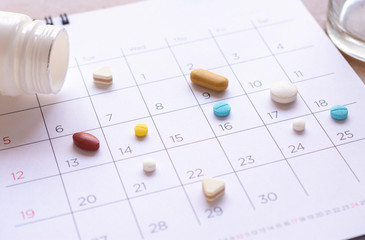 bunch of different pills on a calendar background. concept Healthcare