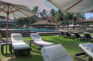 reclining lounge chairs under large umbrellas next to swimming pool