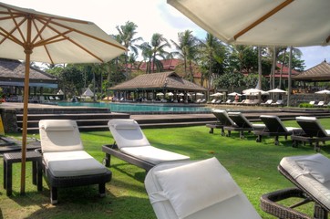 reclining lounge chairs under large umbrellas next to swimming pool