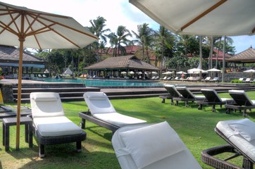 reclining lounge chairs under large umbrellas next to swimming pool