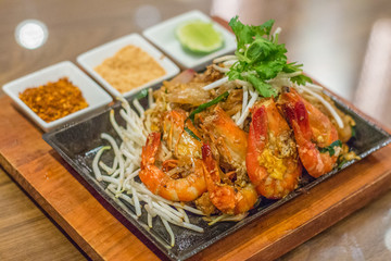 fried pad thai flat rice noodles thai style with prawns and bean sprouts with peanuts and lime on the side