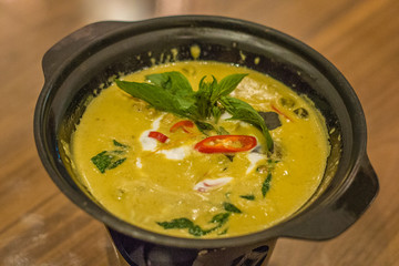 thai style green curry with chilli and thai basil served in a bowl kept warm by a tea light