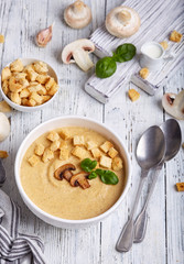 Bowl of champignon mushroom cream soup puree with croutons and basil leaf. Delicious homemade dish. 