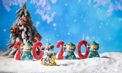 the numbers for the year 2020 stand in the snow with a pine branch decoration and a little imp sit on the left site with a christmas tree in the back on a wooden texture background with shining stars