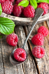 Red fresh raspberries on  rustic wooden background.