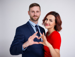 relationship and love concept - portrait of couple in love showing heart shape with hands over white