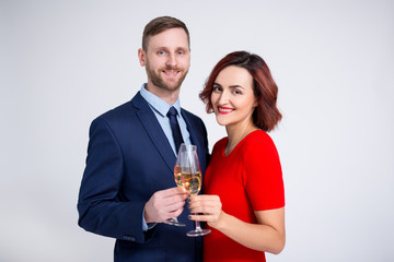 valentine's day, christmas and new year concept - portrait of beautiful couple posing with glasses of champagne over white