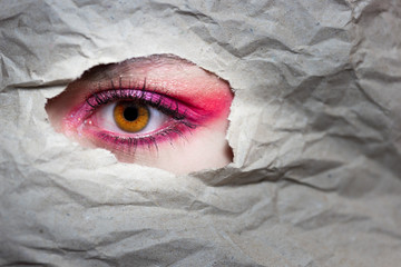 Make-Up Auge Pink / Braunes Auge / Frau schaut durch Papier
